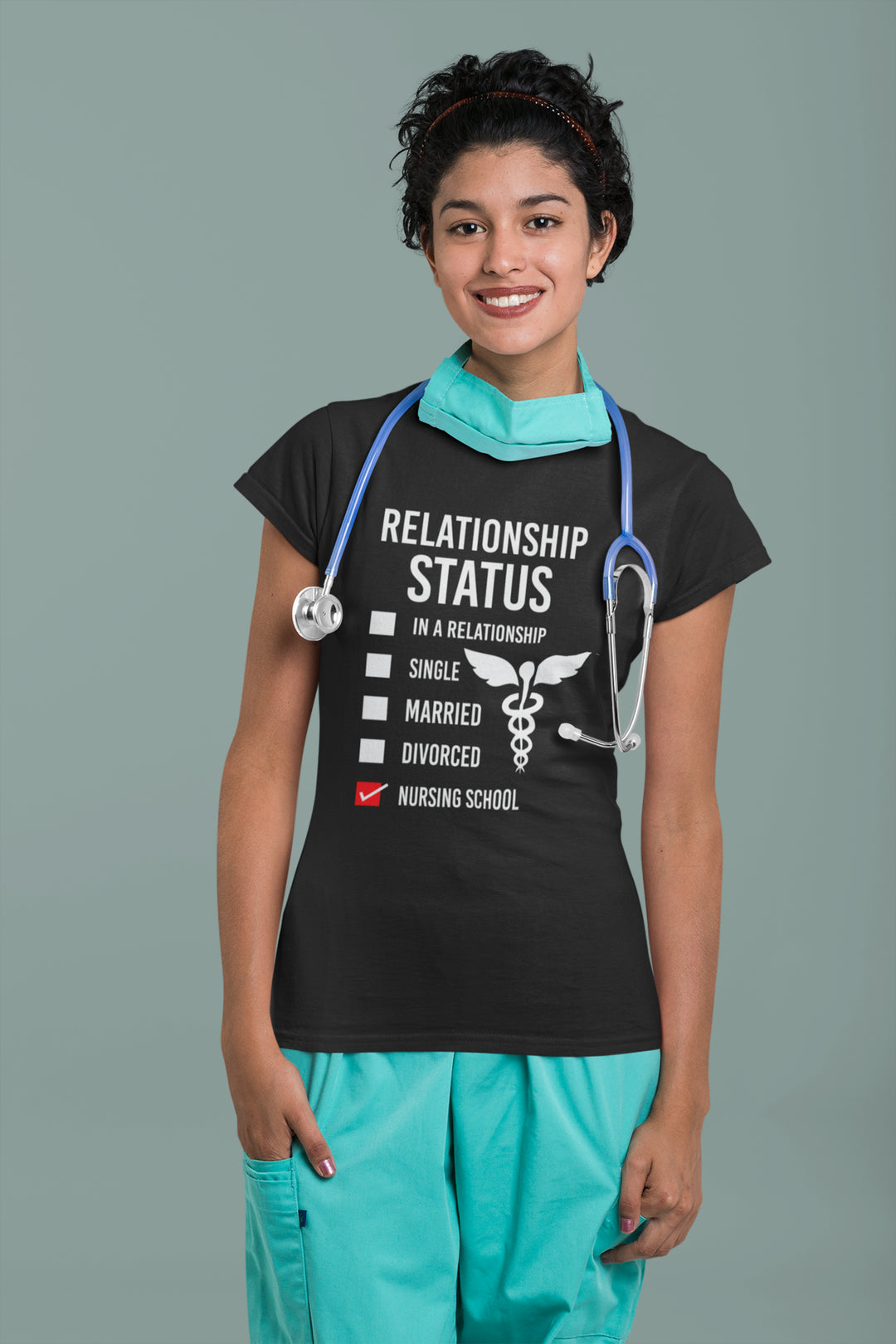 Person wearing a black t-shirt with a humorous relationship status graphic and teal scrubs on a gray background