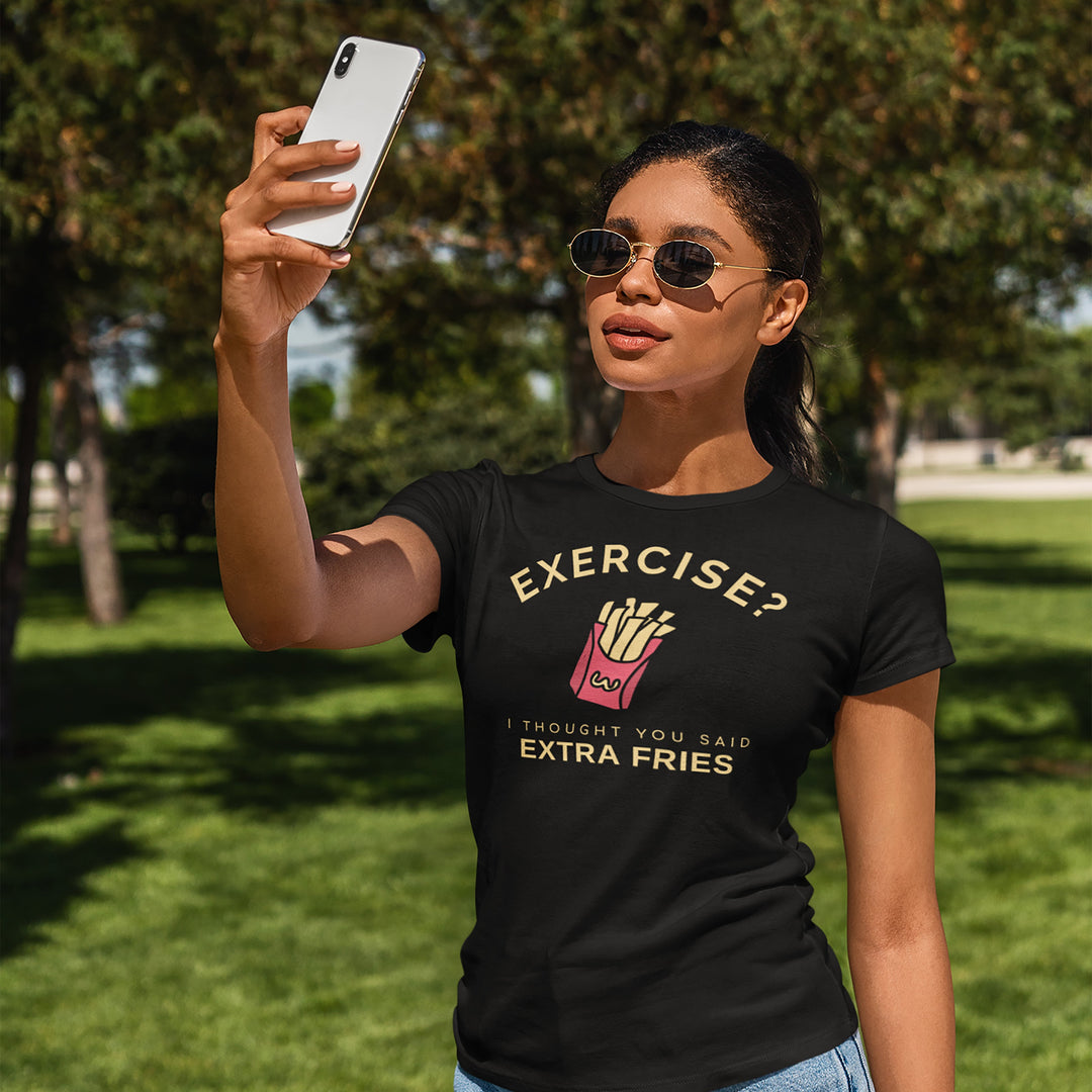 Woman taking a selfie outdoors wearing a black t-shirt with a humorous graphic and text.